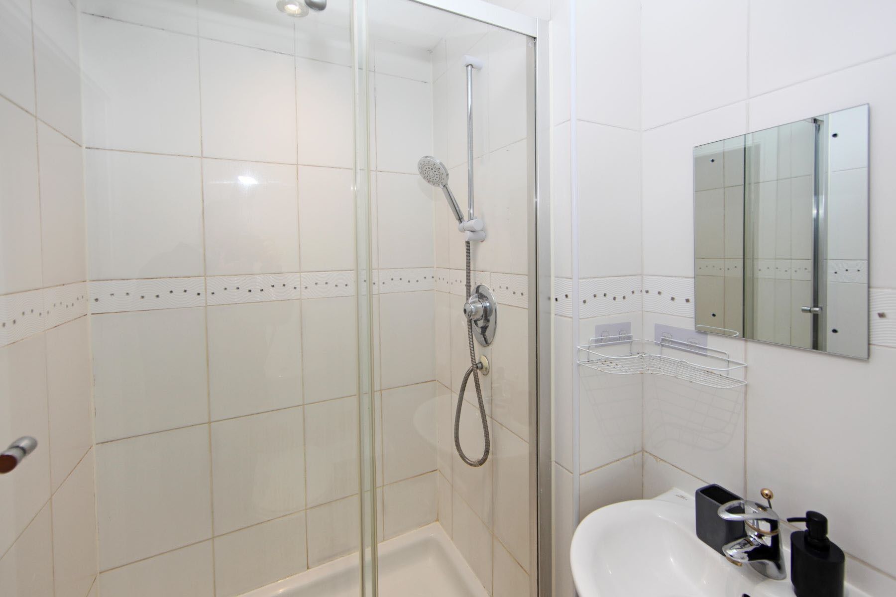A modern bathroom with a glass-enclosed shower, a white sink, and a mirror.