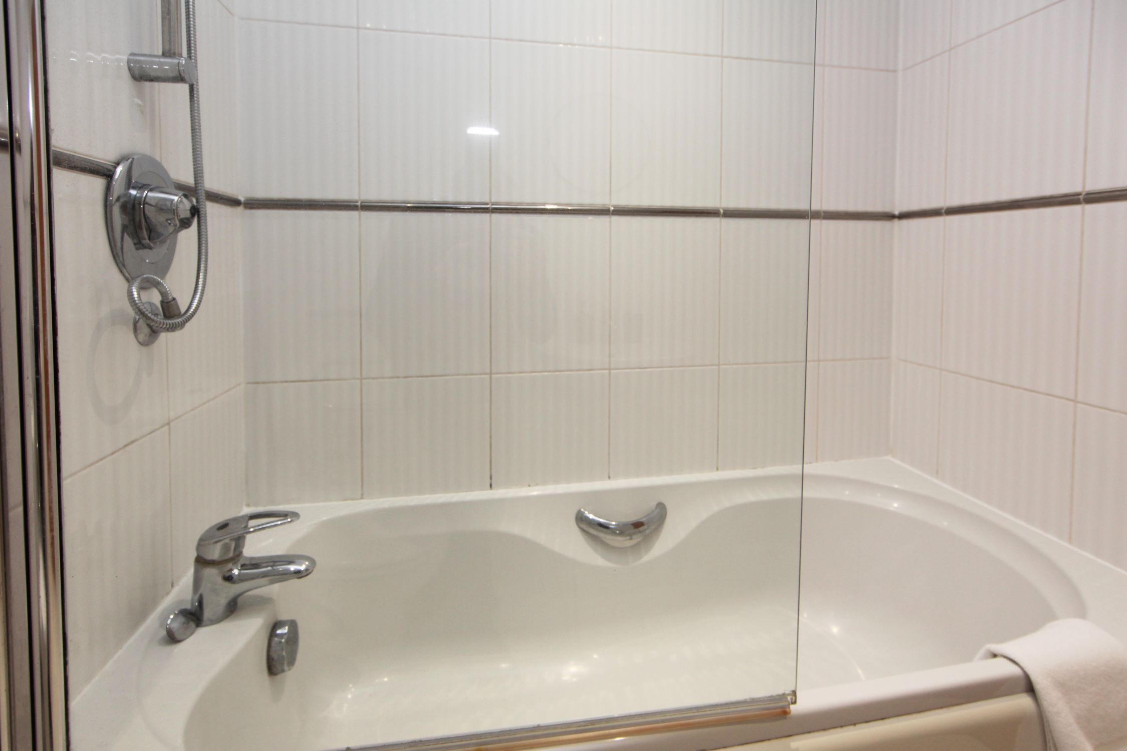 A bathroom with a bathtub, a shower, and a towel rack.