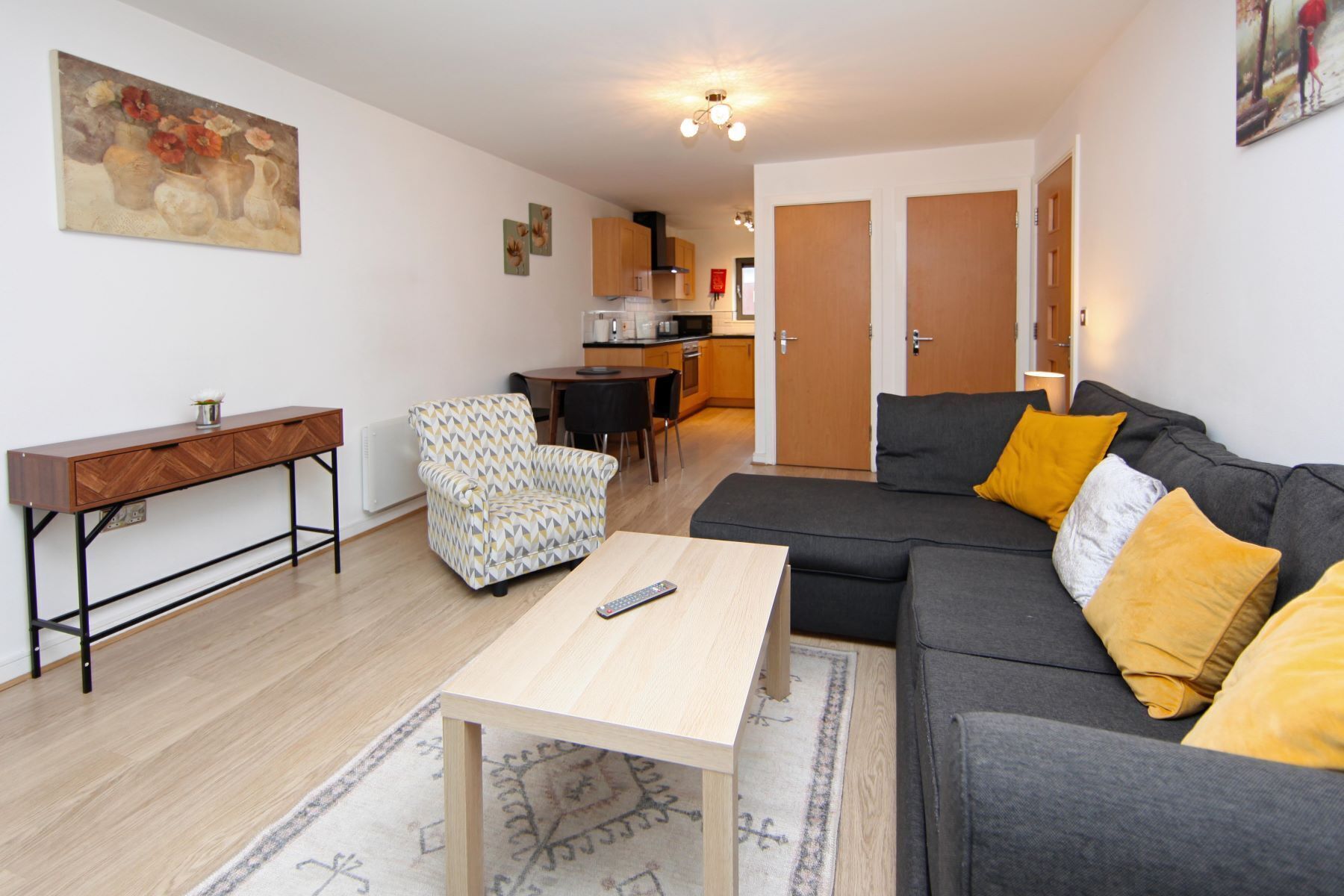 Ein Wohnzimmer mit Sofa, Sessel, Couchtisch und einem Bild an der Wand.