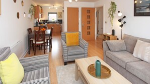 A modern living room with a sofa, armchair, and dining area. - Albion Street Apartments (Wolverhampton)