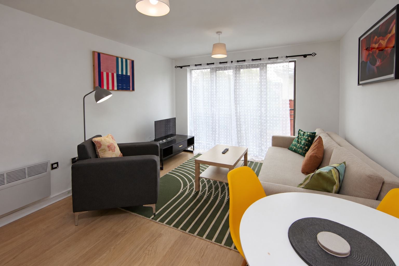 Ein modernes Wohnzimmer mit einer Couch, einem Couchtisch, einer TV-Konsole und einem Essbereich.