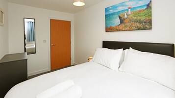Une chambre d’hôtel avec un lit, un bureau, une porte et un tableau au mur.