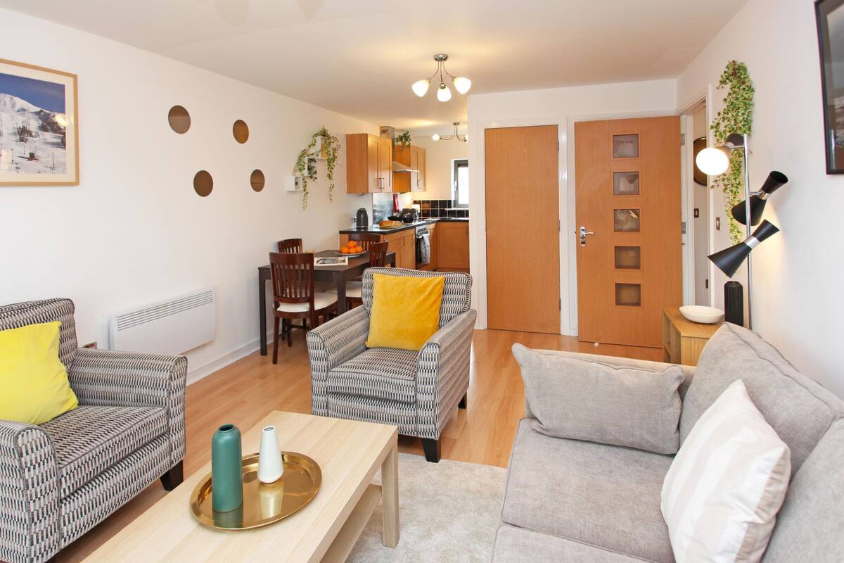 A living room with a sofa, armchairs, a coffee table, and a dining area with a table and chairs.