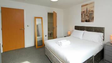 Une chambre d’hôtel avec un lit, une table de chevet, un miroir et une porte.