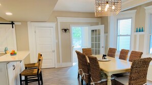A dining area with a long table and wicker chairs, a chandelier, and a view of the outdoors. - Family-Sized with Bay Views and Close to Beach (Ventnor City)