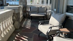 A covered porch with a stone balustrade, a ceiling fan, and a view of the water and buildings in the background. - Family-Sized with Bay Views and Close to Beach (Ventnor City)