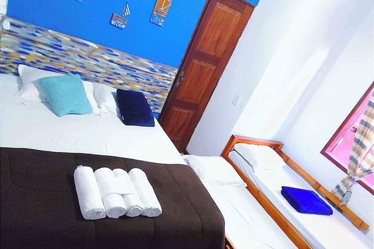 A hotel room with a bed, a sofa bed, and a wooden table.