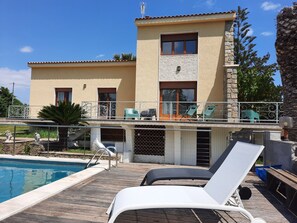 A two-story building with a swimming pool, outdoor seating, and a stone facade. - A magnificent villa with a swimming pool and an outdoor kitchen. (Ventiseri)
