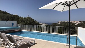 Una piscina con vista al mar y una ciudad al fondo.