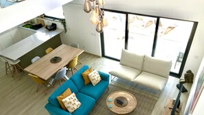 Un espacio habitable moderno con comedor, sofá y vistas amplias a través de grandes ventanales.