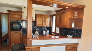 Eine Küche mit Holzausstattung, einer Marmorarbeitsplatte und einem eingebauten Backofen.