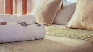 A neatly made bed with a textured bedspread and several pillows, including a decorative one with a chevron pattern. - Bon Amour Punta del Diablo (Punta del Diablo)