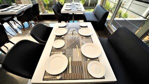 Un comedor con una mesa rectangular dispuesta para cuatro personas, rodeada de sillas negras.