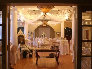An elegantly decorated room with a chandelier, draped fabric, and floral arrangements.