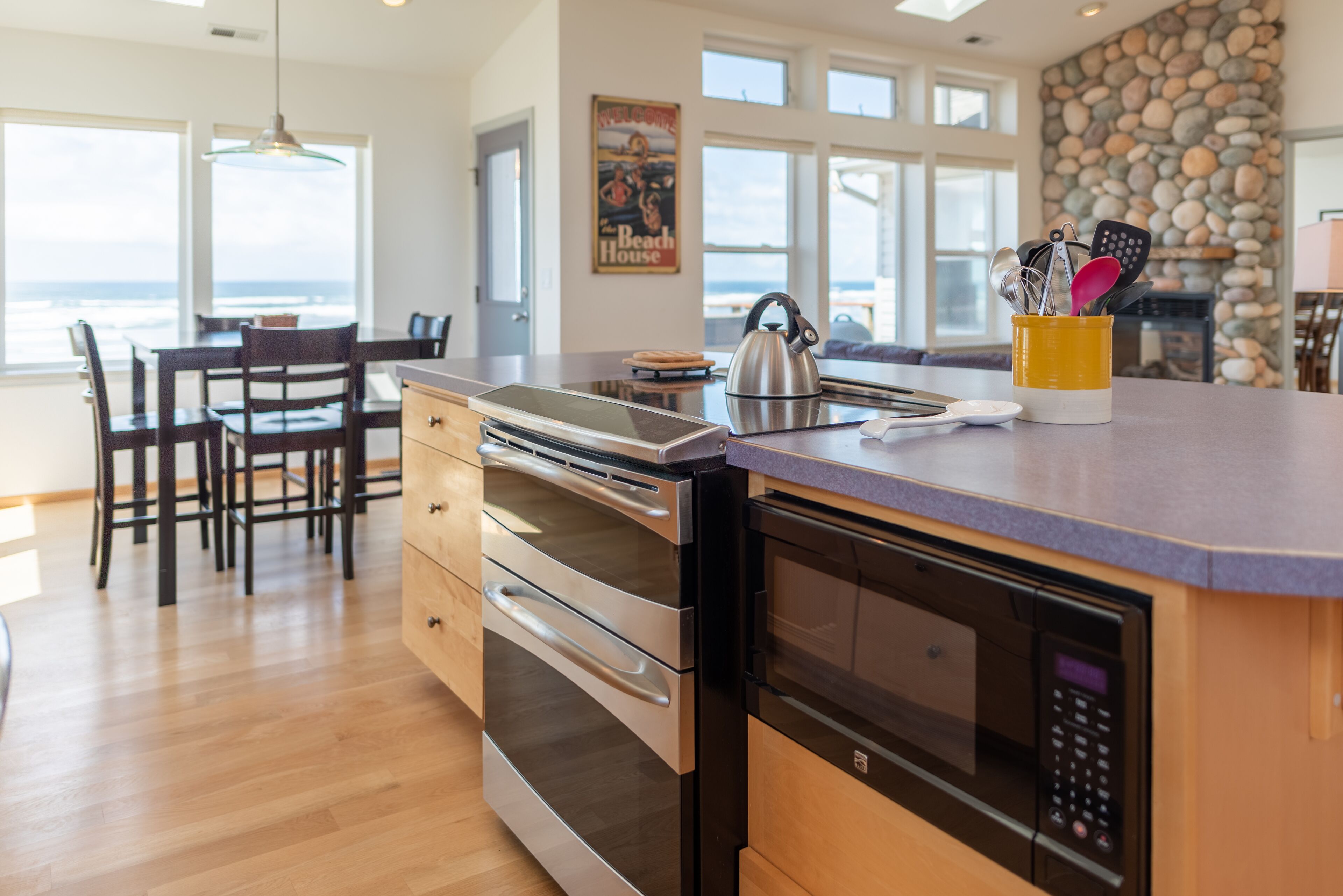 A modern kitchen with a stone wall, stainless steel appliances, and a dining area with a view.