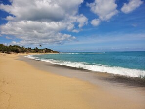 Una playa con cielos despejados y olas tranquilas.