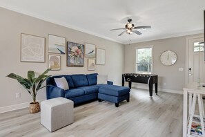 A living room with a sectional sofa, ottoman, and a foosball table.