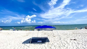 A beach with a blue umbrella and a black mat on the sand. - New! 5 min to beach! Clean, modern and spacious-King mattress on Primary room  (Pensacola)