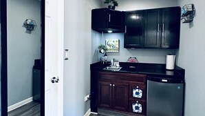 A compact kitchen with dark cabinets, a refrigerator, and a countertop.