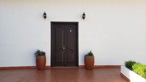Una puerta doble de color marrón oscuro con el número 8, flanqueada por dos macetas con diseños decorativos.