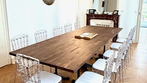 A conference room with a wooden table, clear plastic chairs, a large mirror, and a decorative fireplace. - Gîte Vichy - 4 Chambres, Situé Dans le Parc du Château de Charmeil (Charmeil)