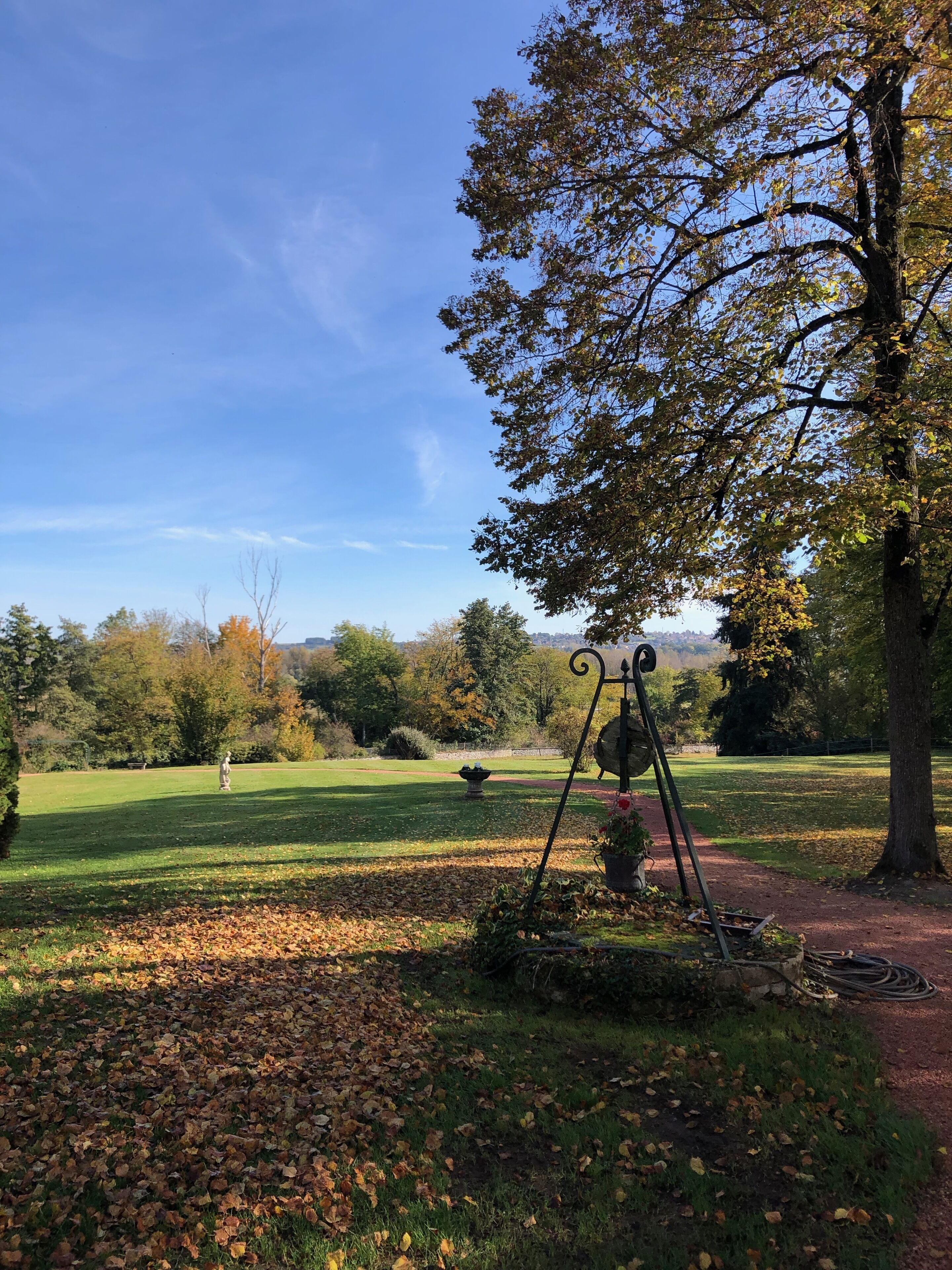 A park with a swing set, a statue, and a fountain.