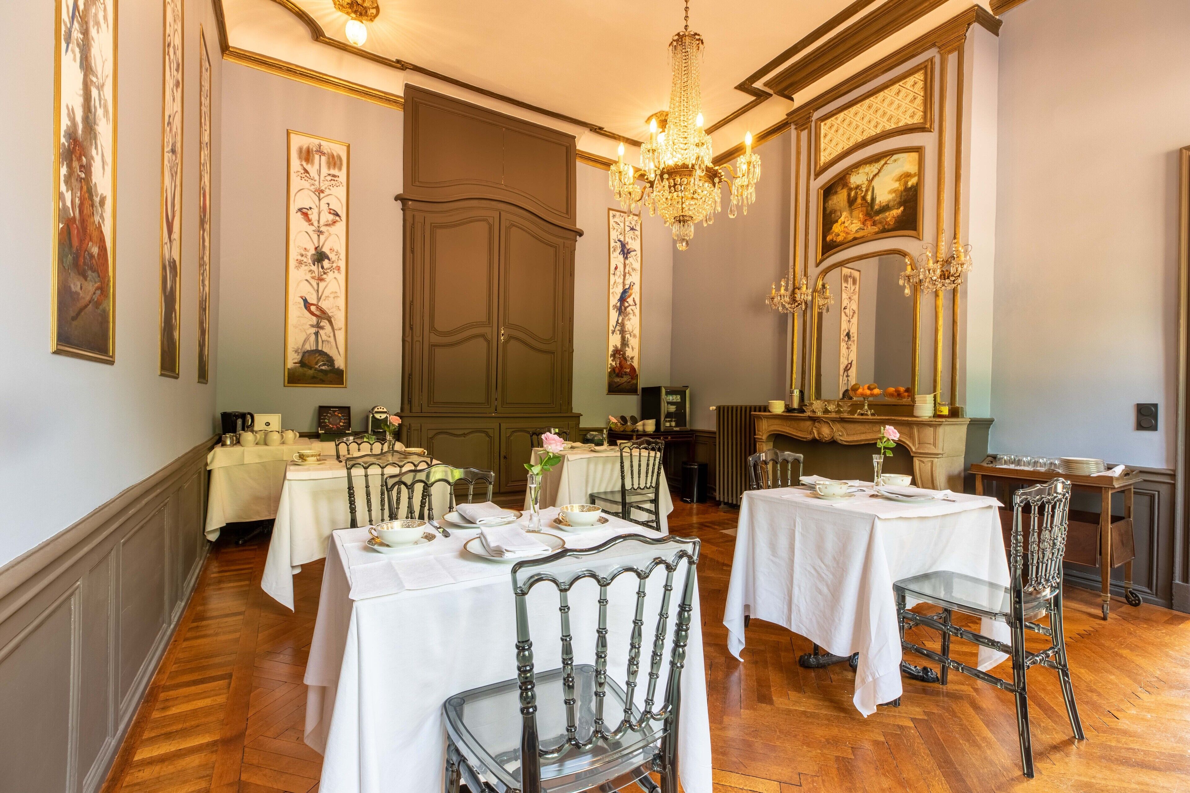 Ein formeller Speisesaal mit mehreren gedeckten Tischen, eleganten Kronleuchtern und klassischen Wanddekorationen.