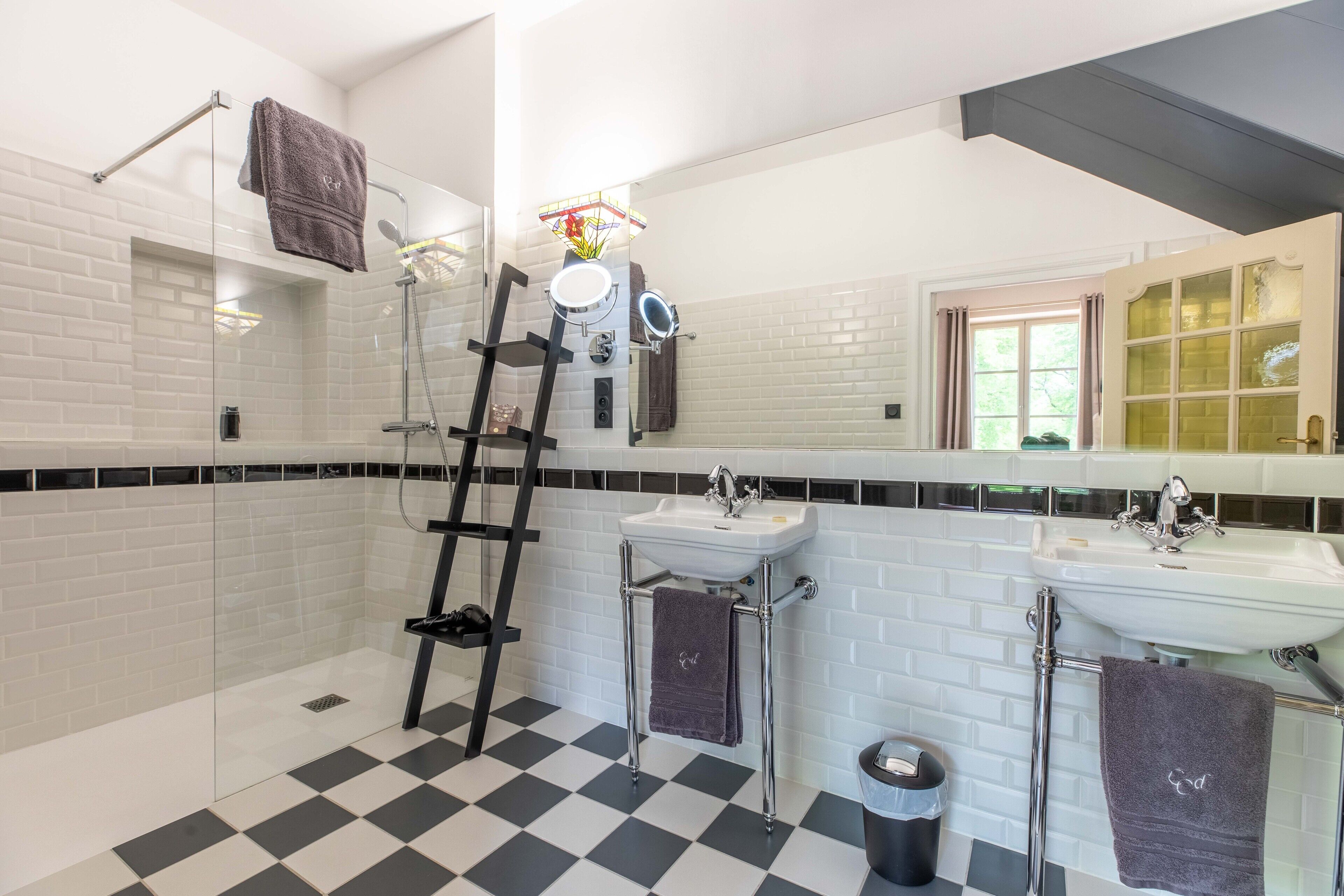 A bathroom with a checkered floor, two sinks, a shower, and a ladder.
