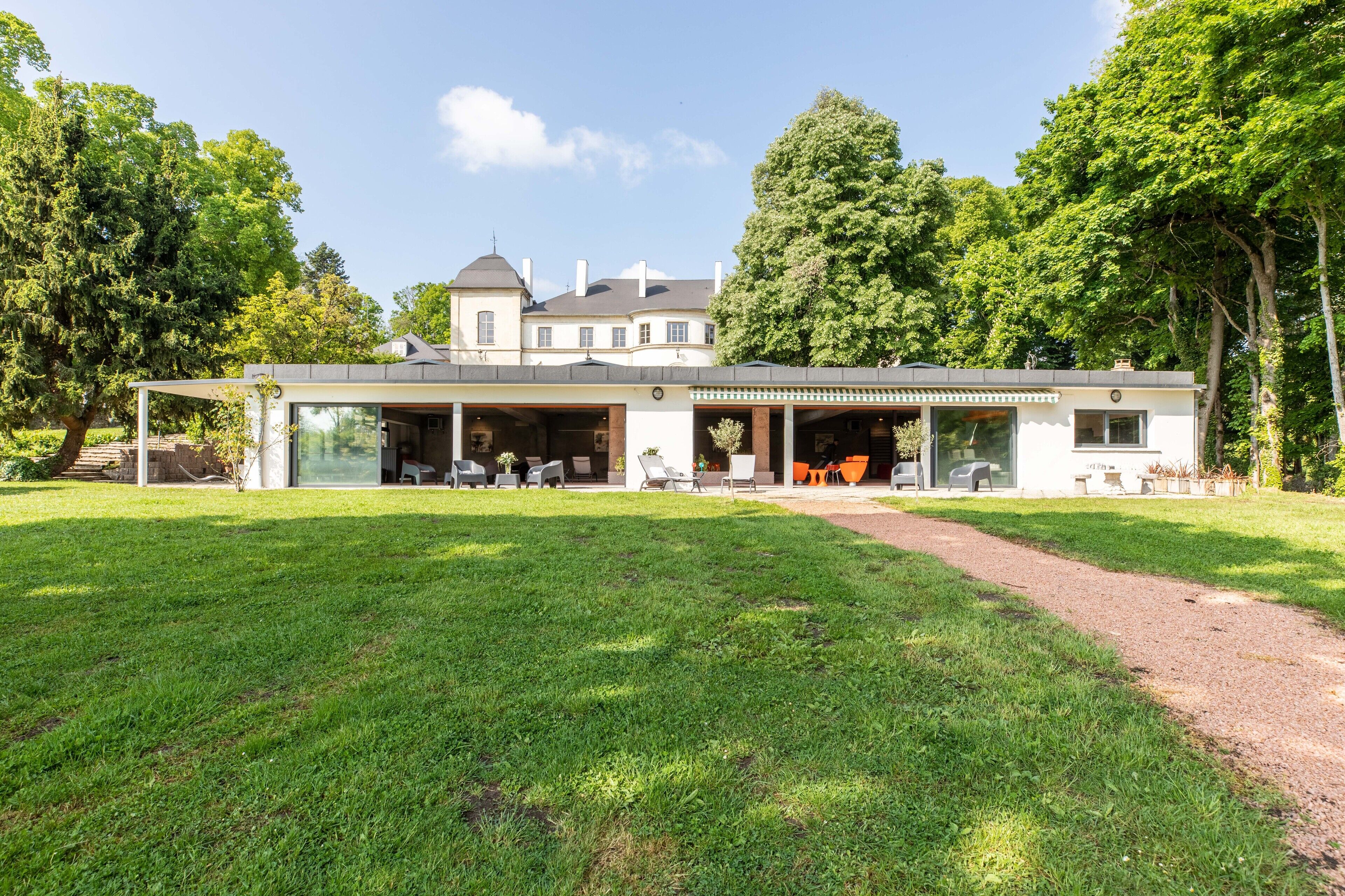 Una casa moderna con un porche cubierto, ventanas amplias y un césped.