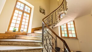 A spiral staircase with a wooden handrail and black metal balusters, leading to an upper floor. - Chambres D'hôtes Vichy : Château de Charmeil (Charmeil)
