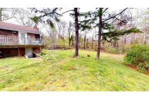 Set amidst a serene wooded area, this two-story house offers a balcony and a beautifully manicured lawn.