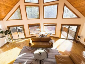 Relax in a spacious room with a high ceiling, sofa, and large windows offering views of the surrounding area.
