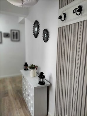 Un pasillo con una consola blanca, espejos decorativos y un panel de tela a rayas.