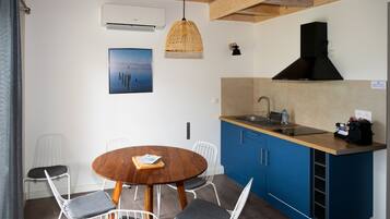 Una cocina compacta con armarios azules, una mesa de comedor de madera y una lámpara colgante.