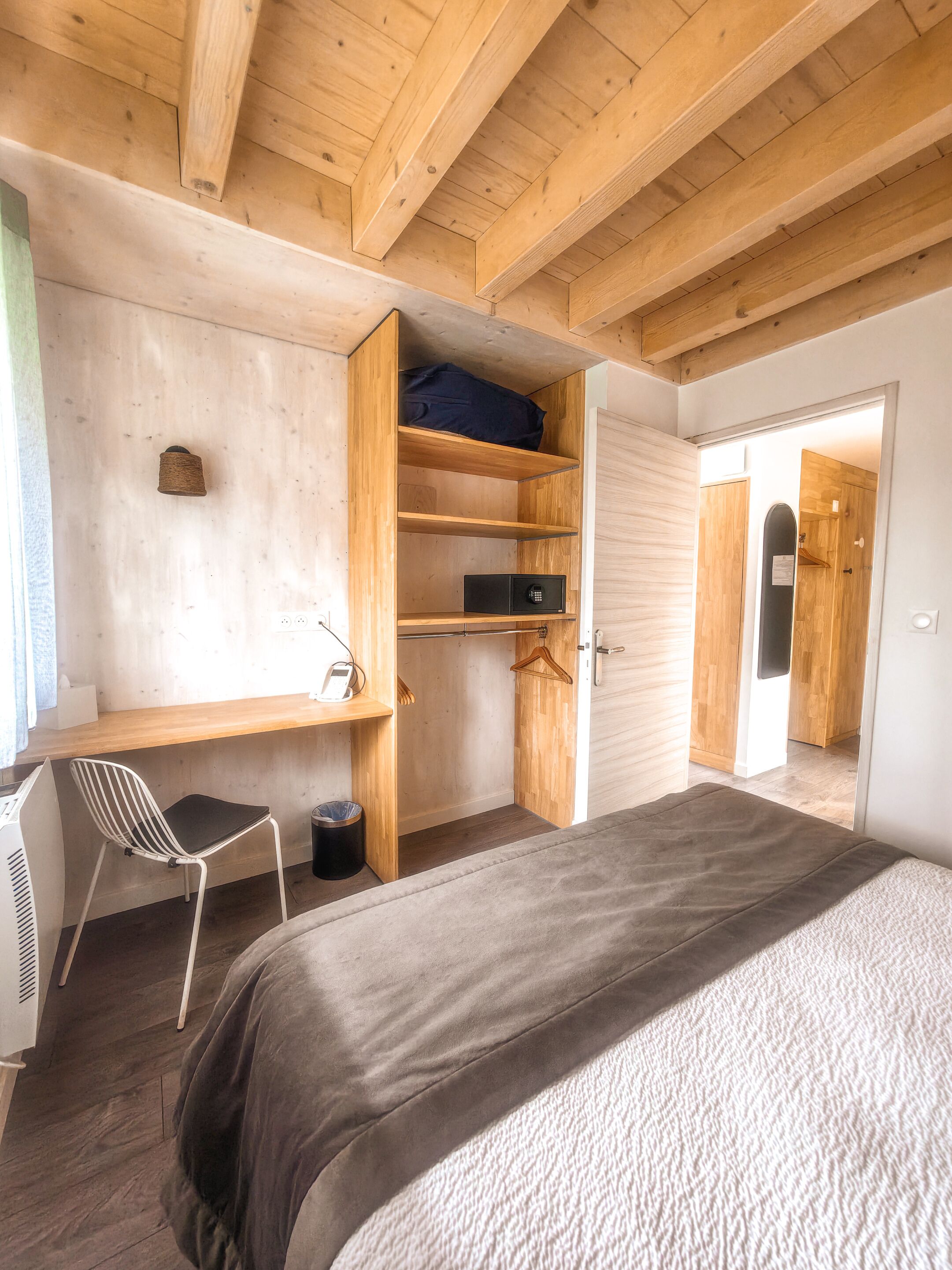A bedroom with a bed, a desk, and a wardrobe.