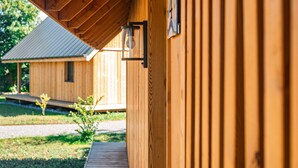 Un edificio de madera con un corredor cubierto y un pequeño jardín.