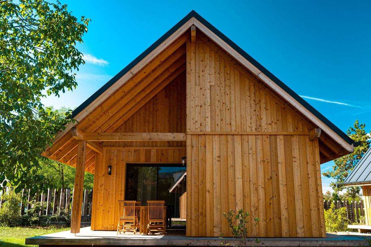 Een houten chalet met schuin dak, een overdekte veranda en een grote schuifpui.