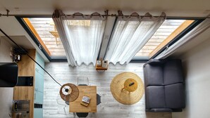 Un espacio habitable compacto con tragaluces, una mesa de comedor con sillas, un sofá y una pequeña zona de cocina.
