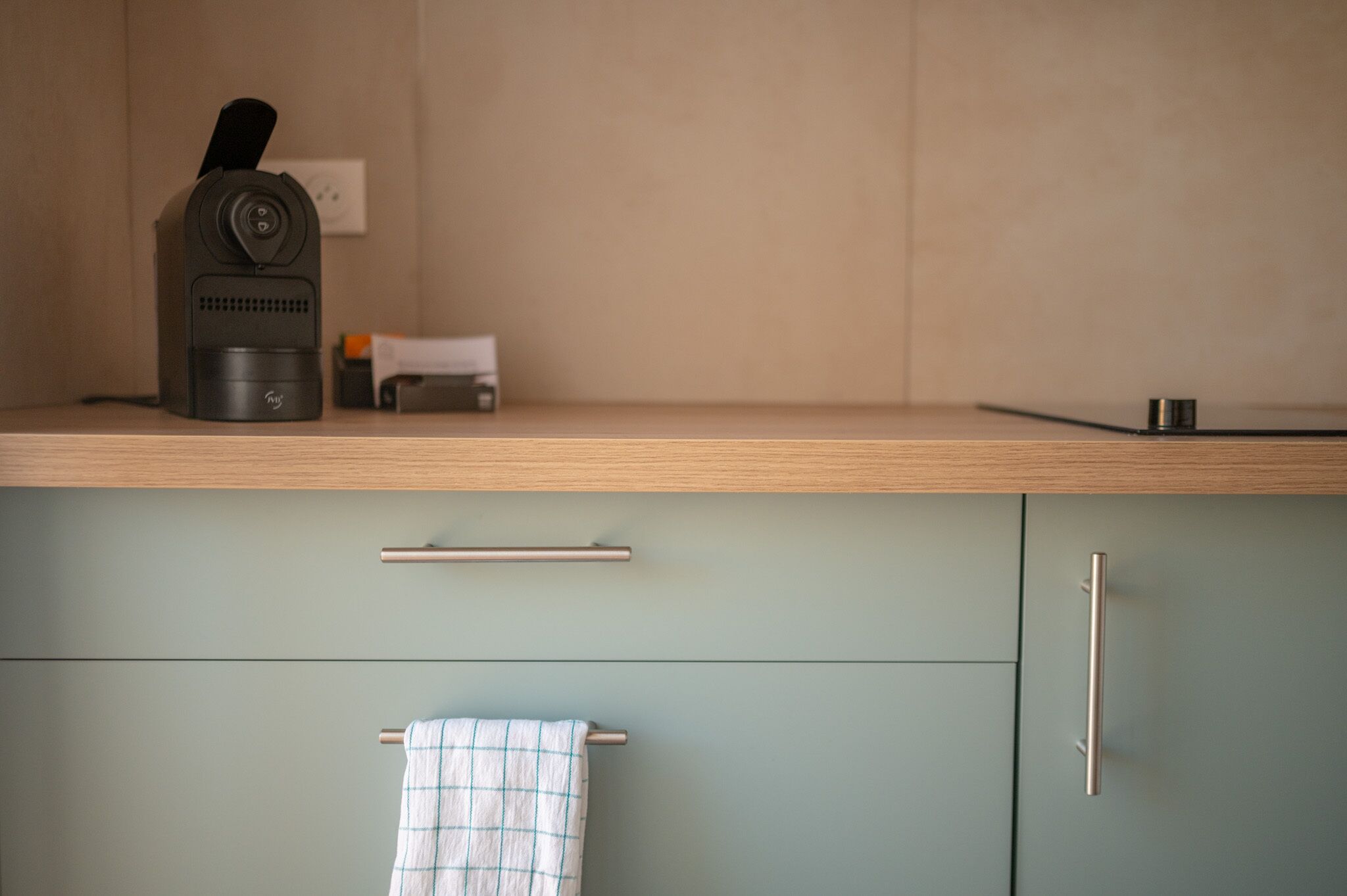 Une cuisine équipée d’une machine à café, d’un petit appareil électroménager et d’une serviette suspendue à un porte-serviettes.