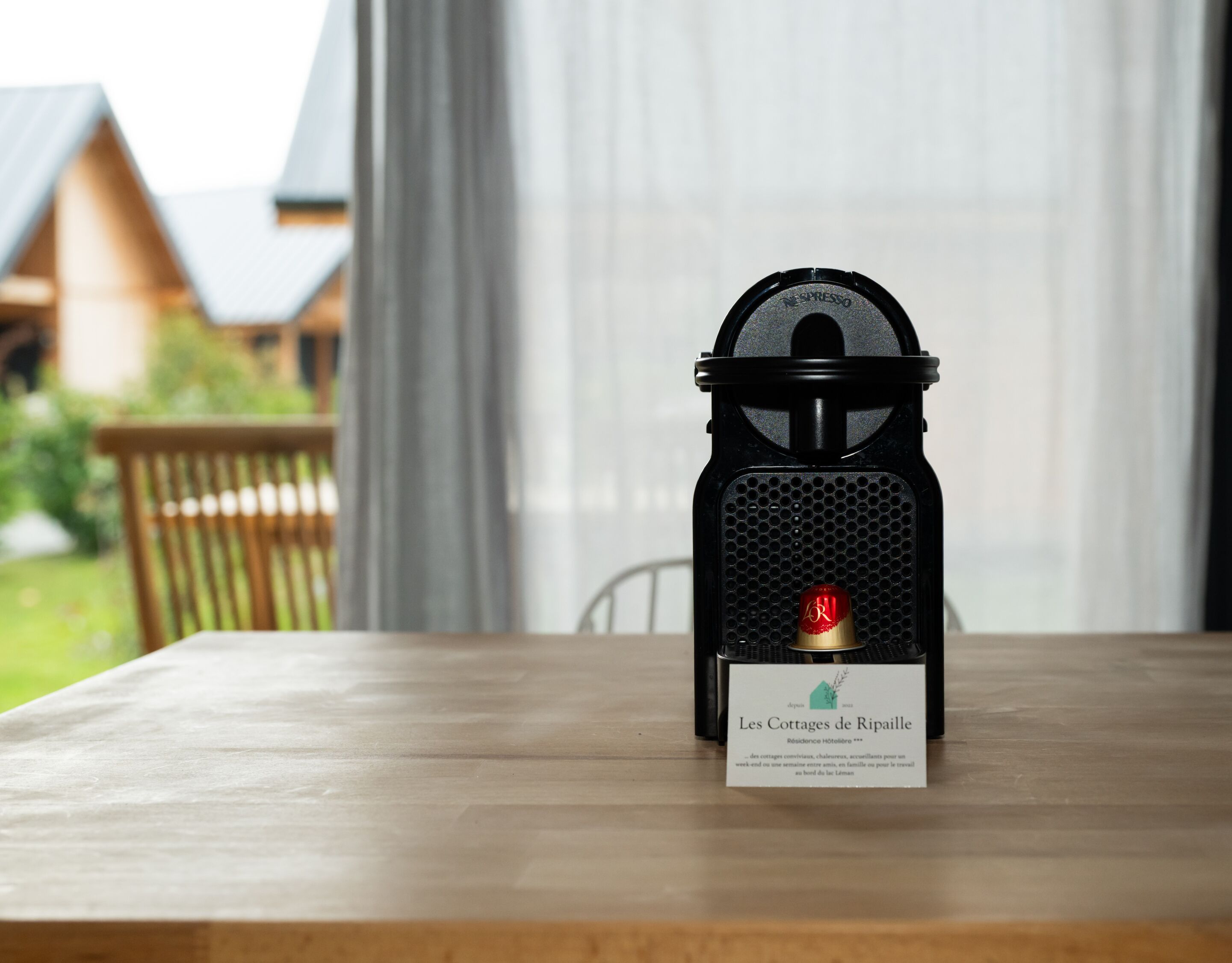 Máquina de café espresso preta com uma etiqueta sobre uma mesa de madeira.