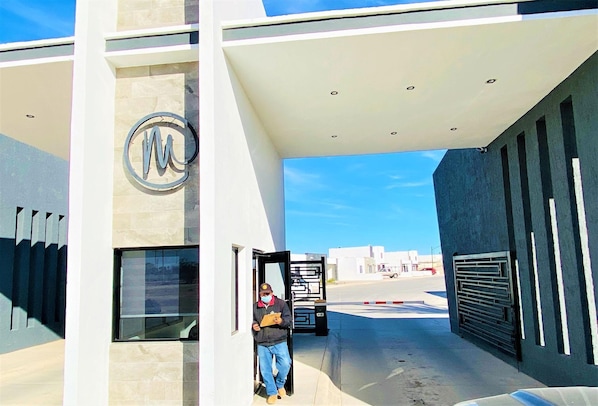 A modern building entrance with a large logo, a glass door, and a metal gate. - STUNNING 3 BED HOME - 2 POOLS - GATED COMMUNITY- CLOSE TO SANDY BEACH (Puerto Peñasco)