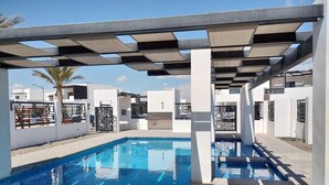 Ein moderner Poolbereich mit kariertem Deckenmuster, weißen Wänden und einem klaren, blauen Pool.