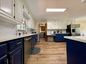 A kitchen with white cabinets, blue countertops, and a wooden floor.