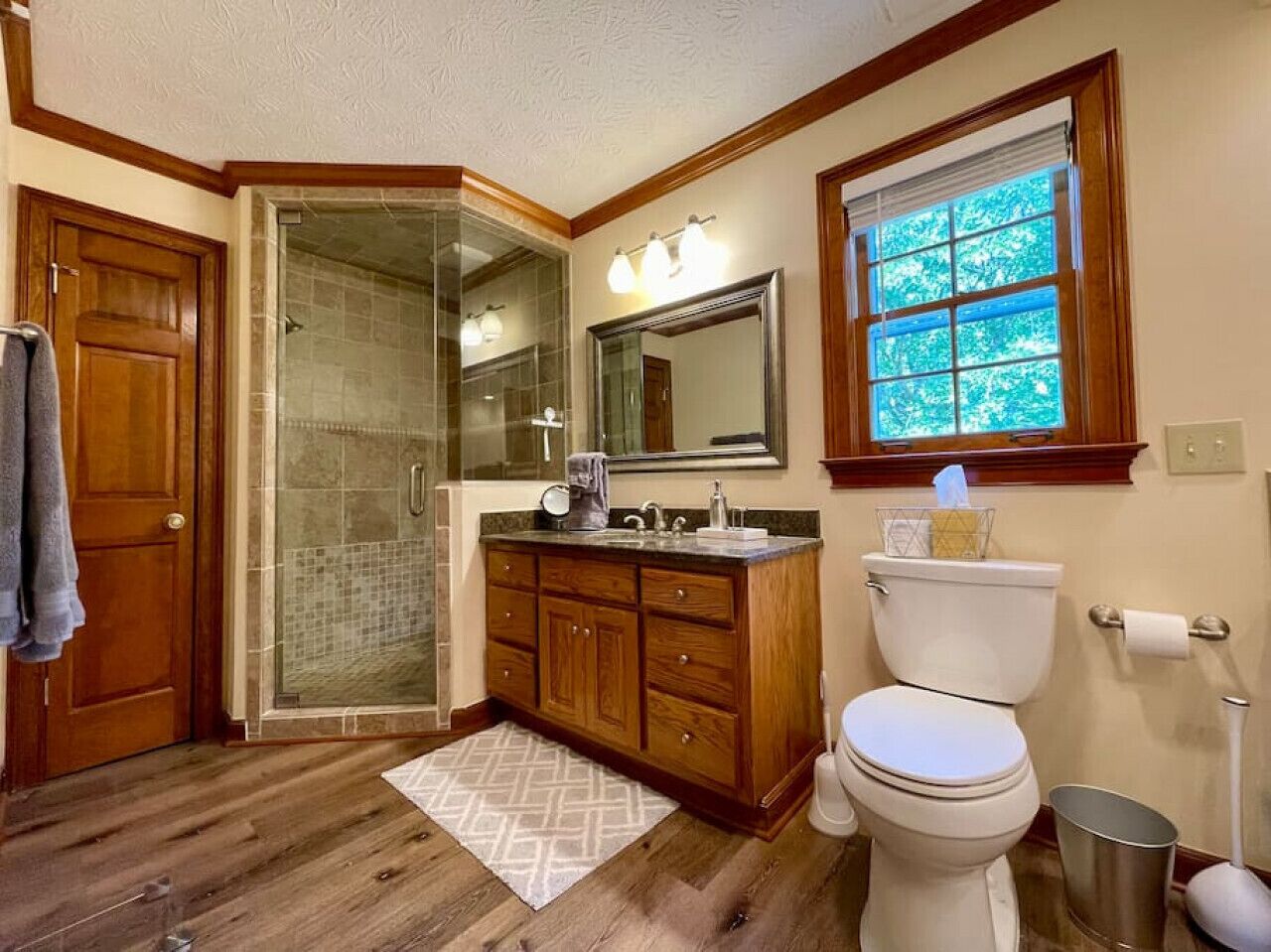 Une salle de bain avec une douche à parois de verre, un meuble-lavabo en bois et des toilettes.