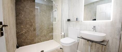 Une salle de bain moderne avec une douche à parois de verre, des toilettes et un lavabo avec un miroir au-dessus.