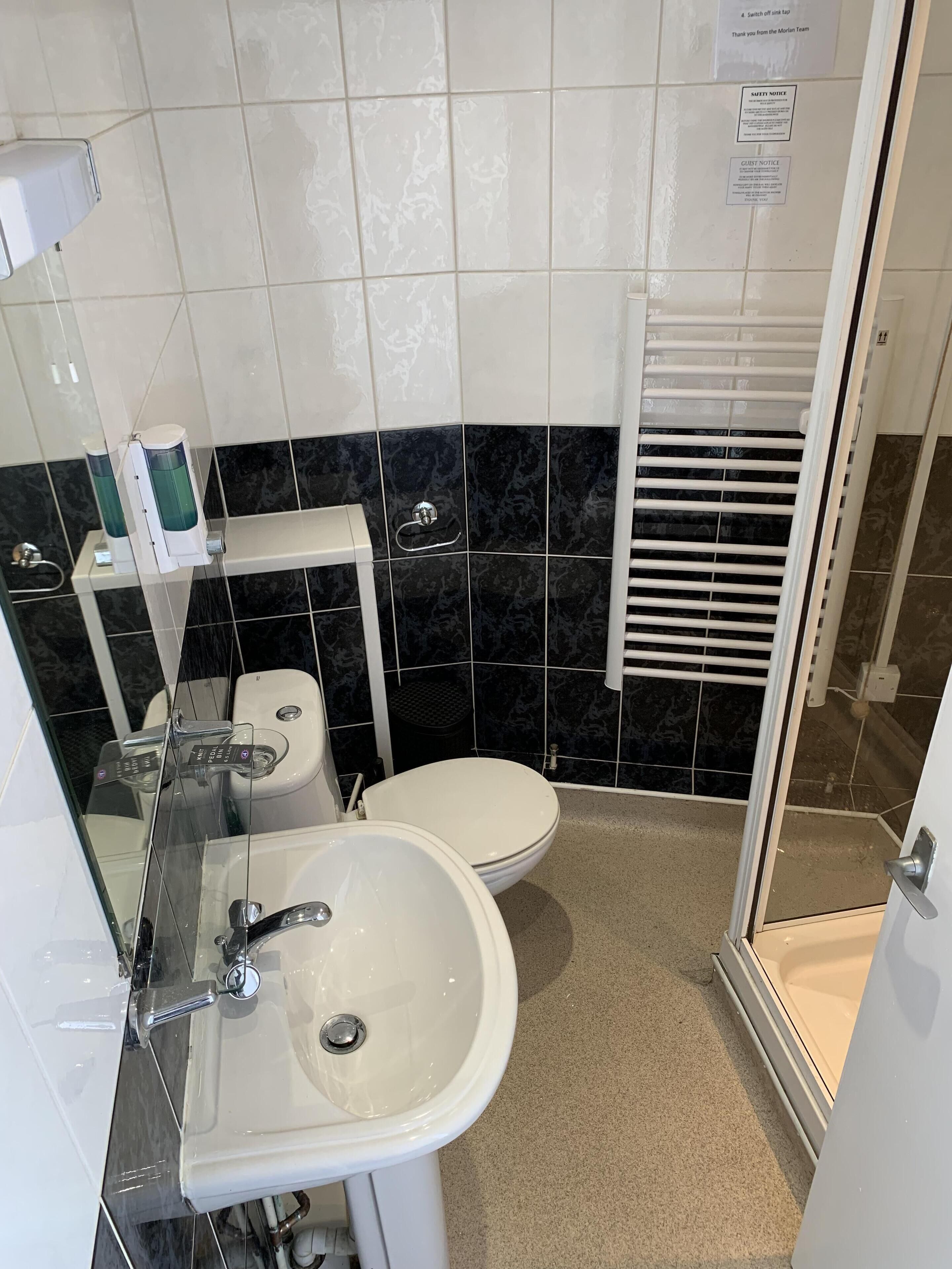 A compact bathroom with a white sink, toilet, and shower area.