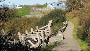 A pathway leading to a blue building with a 'Take Away Cafe' sign. - Traeth Rooms (Cardigan)