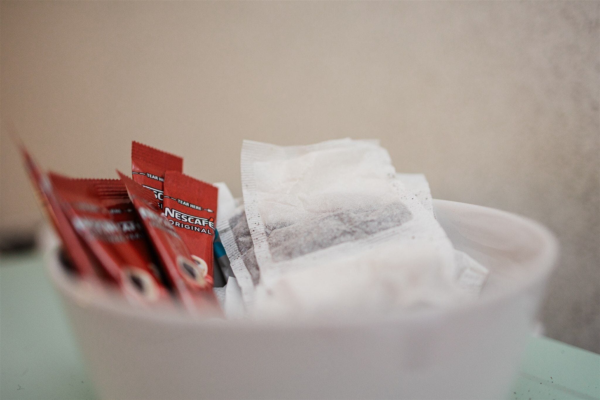 A bowl containing tea bags and a white cup.