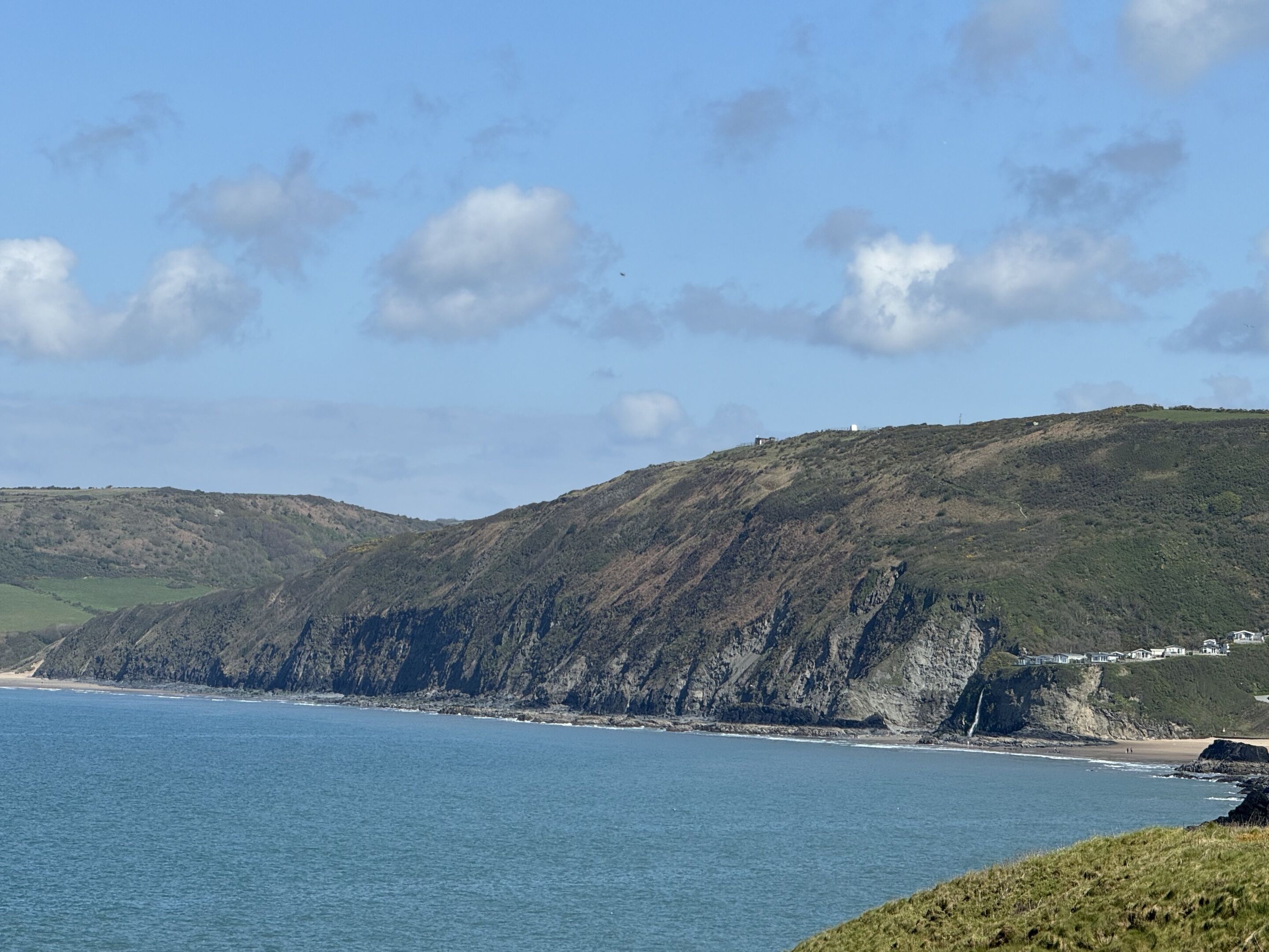 Paisaje costero con vista despejada al mar y montañas al fondo.