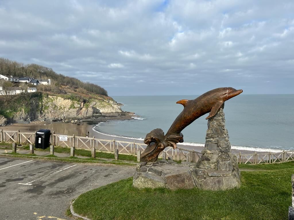 Una escultura costera con vistas al mar y casas al fondo.